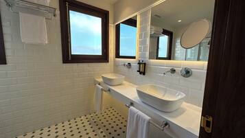 A modern bathroom with a white sink, a large mirror, and a window.