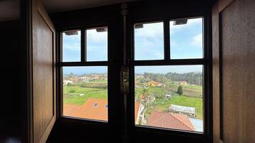Habitación con dos ventanas que dan a zona residencial con casas y vegetación.