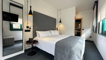 Una habitación de hotel moderna con una cama grande, mesitas de noche, un espejo y un armario.