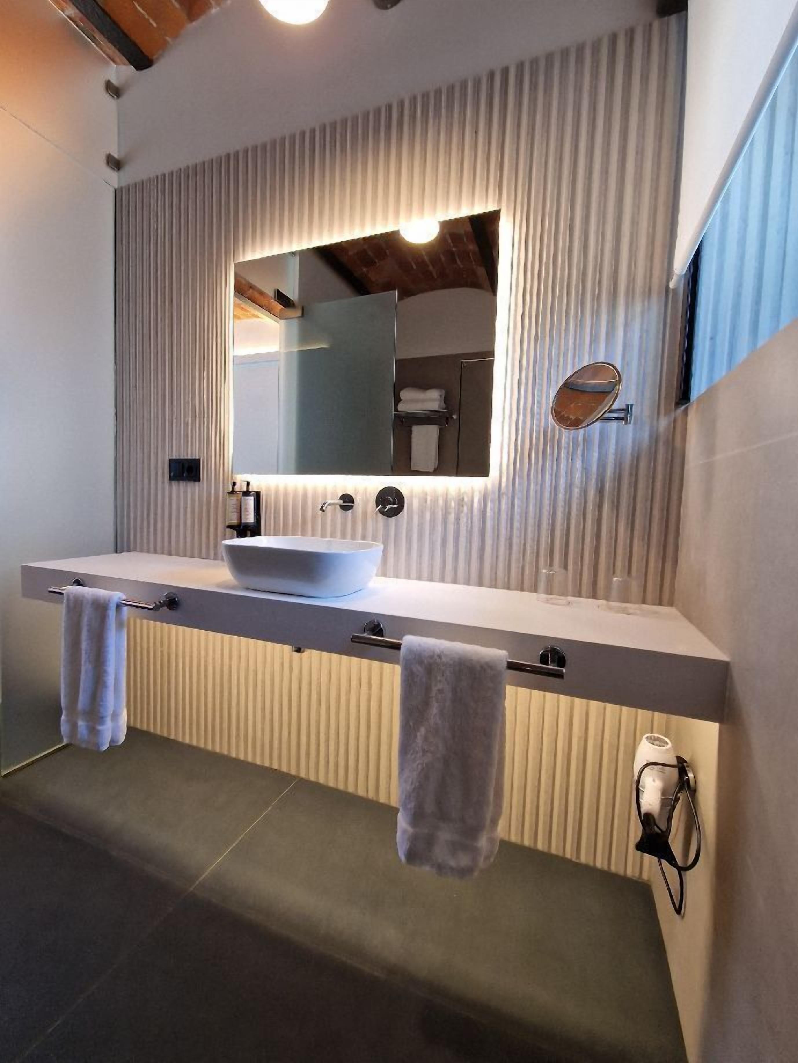Een moderne badkamer met een grote spiegel, twee wasbakken en een handdoekrek.