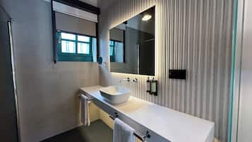 Un baño moderno con un lavamanos grande, un espejo y un perchero para toallas.