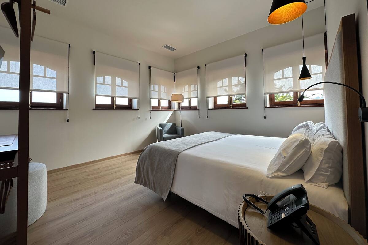 A bedroom with a bed, bedside table, lamp, and a telephone.