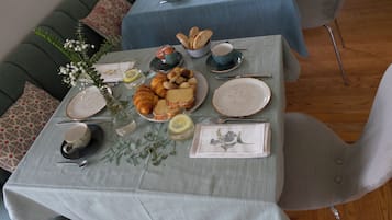 Ein Esstisch ist gedeckt mit Tellern, Brot und einer Blumenvase.