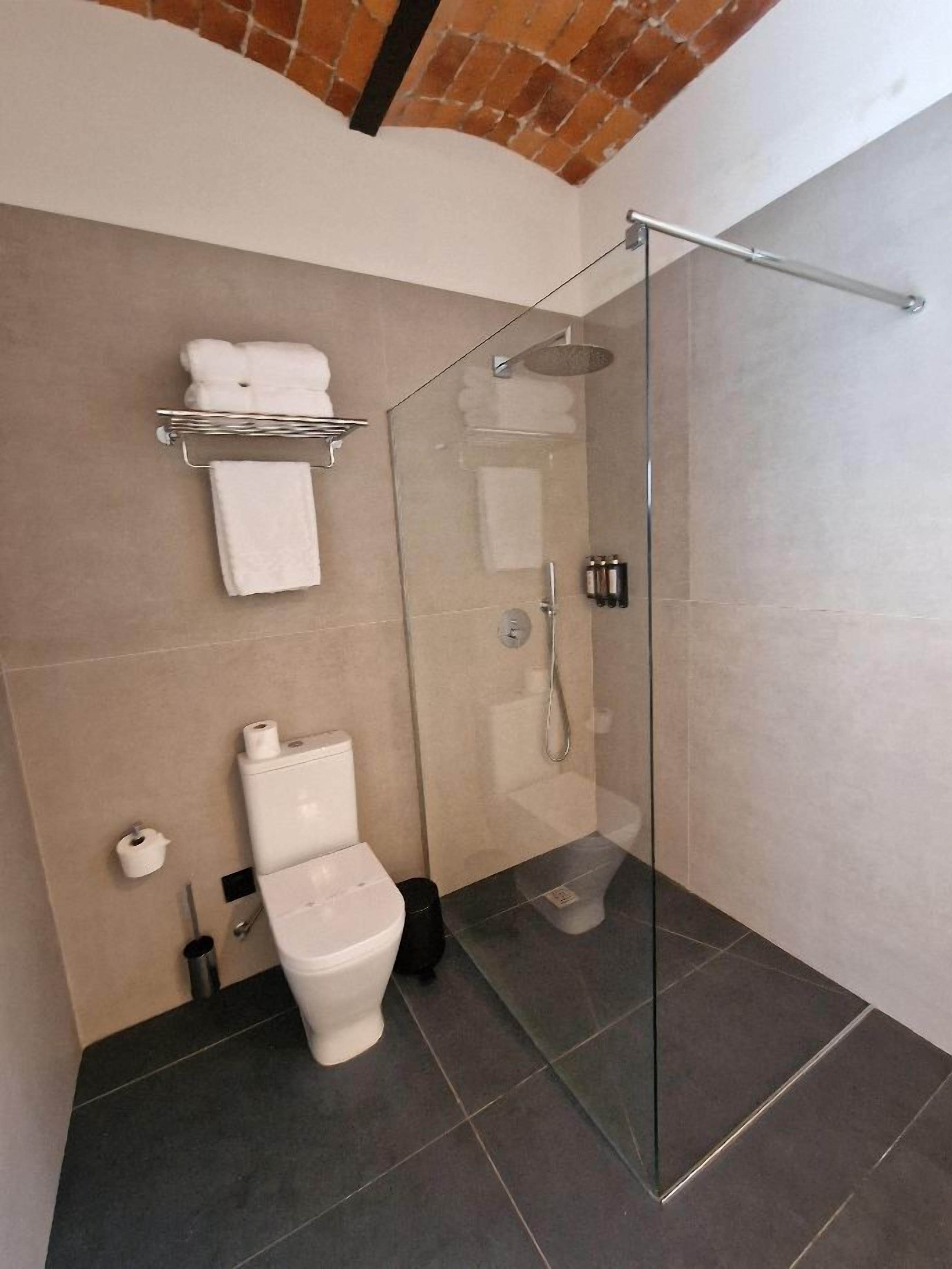 Een moderne badkamer met een douchecabine van glas, een toilet en een handdoekhouder.