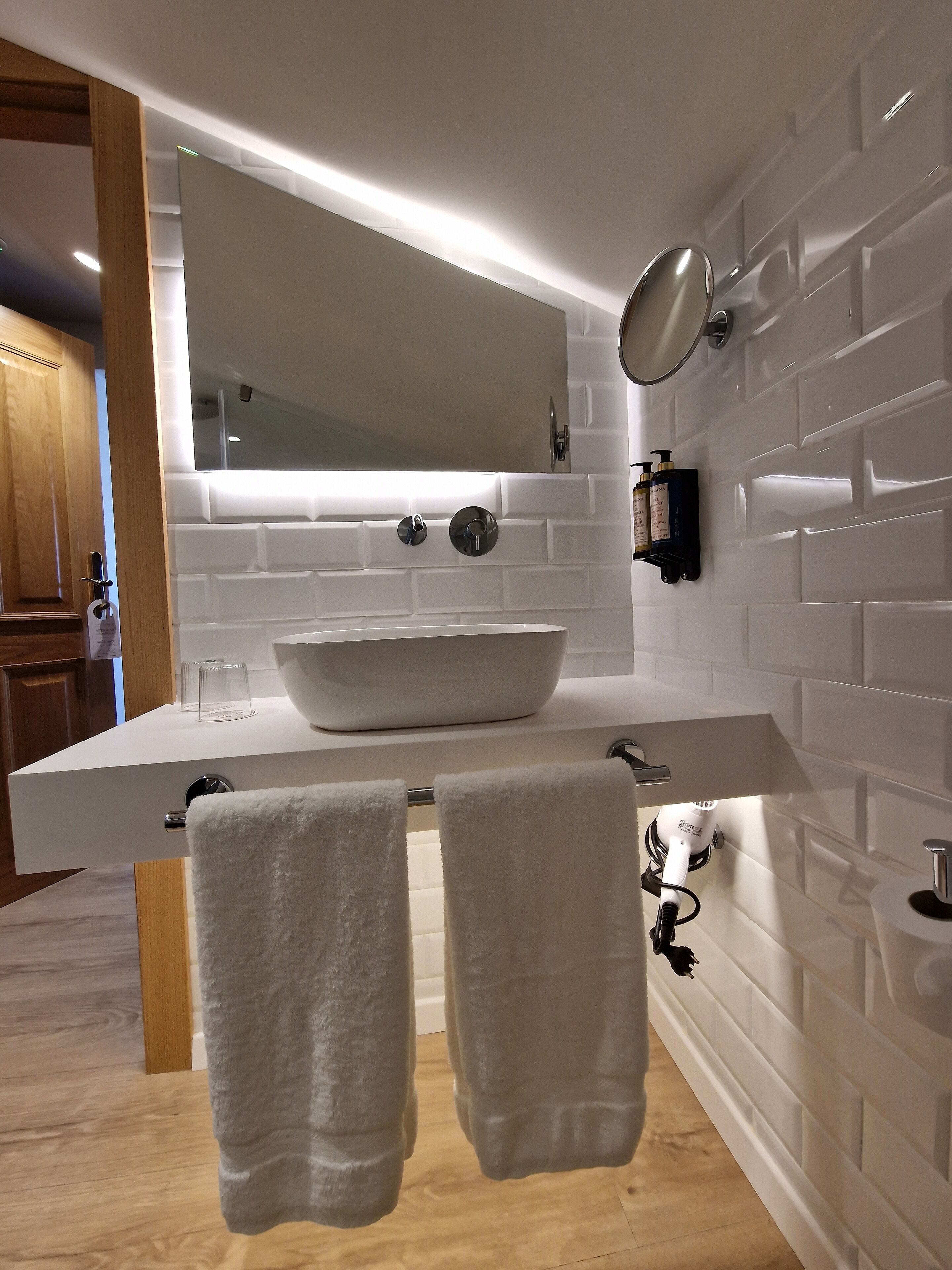 A modern bathroom with a large white sink, a mirror, and two towels hanging on a rack.
