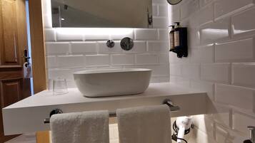 A modern bathroom with a large white sink, a mirror, and two towels hanging on a rack.
