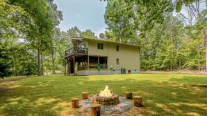 A two-story house with a deck, surrounded by trees and a fire pit in the yard. - Lake Anna • Lake Access • New Boat Dock • Fast WiFi • Small Dog Friendly (Mineral)