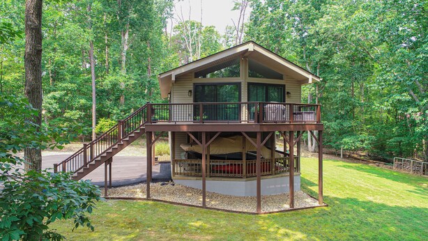 A two-story cabin with a balcony and a covered deck area.