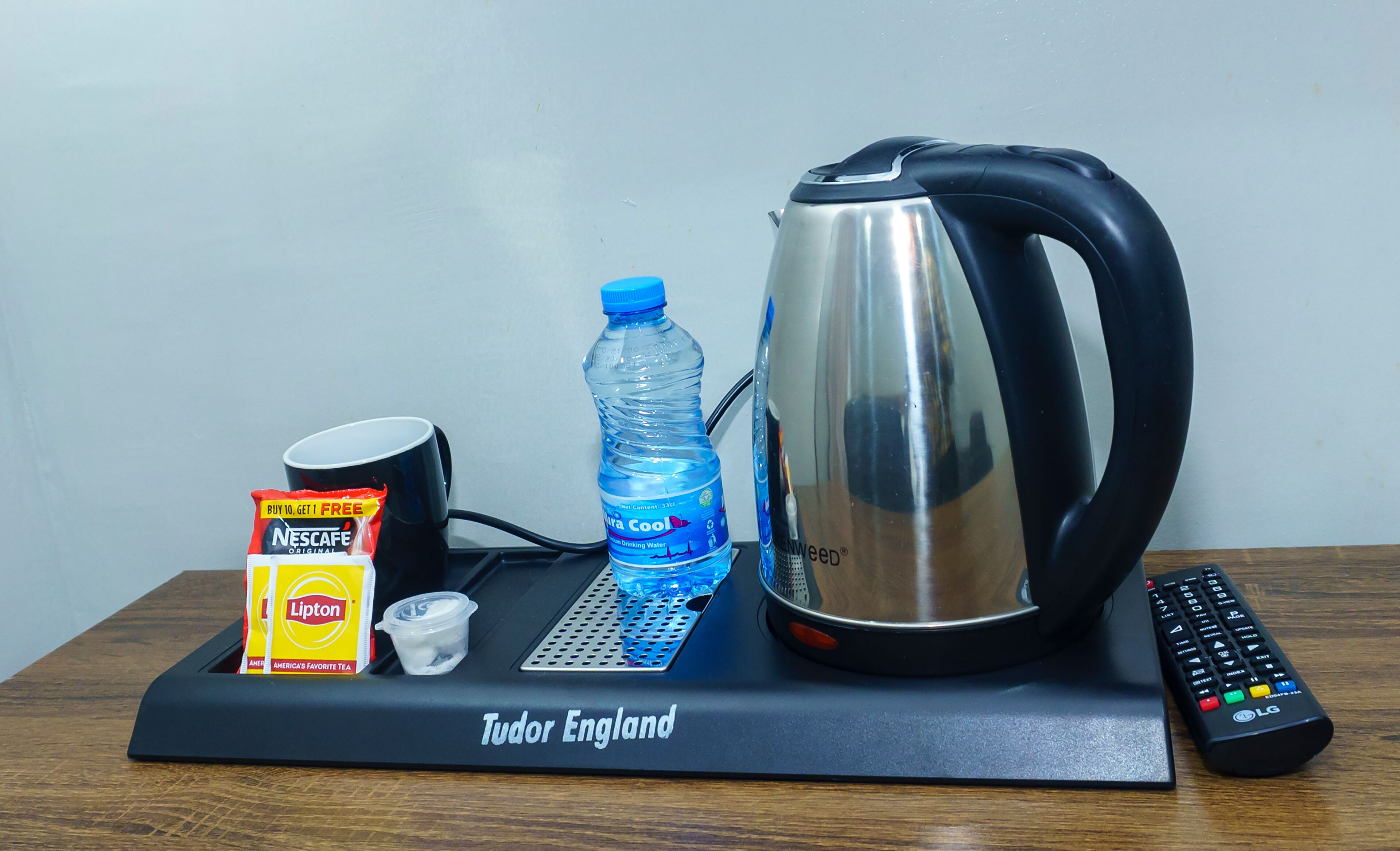 Et bakkejulebord med Lipton te, en vandflaske, en elkedel og en fjernbetjening.
