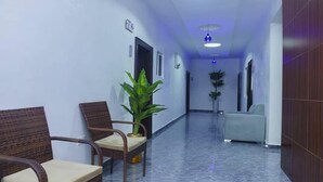 A hallway with wicker chairs, a potted plant, and a sofa. - Bethel Hotel and Suites (Abuja)