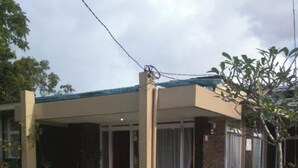 A two-story house with a covered porch and a small garden area. - EXPRESS O 92070 Mando Homestay Syariah Near KANTOR LURAH Bukik Apik Puhun (Bukittinggi)