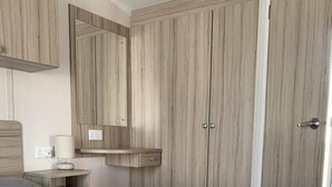 A neatly made bed with a grey comforter, a bedside lamp, and a wooden wardrobe with two doors. - Hot tub Break Away Castle View (Lincoln)