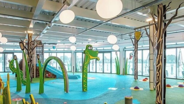 An indoor play area with colorful play structures and a blue floor. - Hot tub Break Away Castle View (Lincoln)