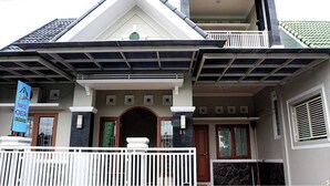 Una casa de dos pisos con un balcón, una puerta principal y un pequeño porche.