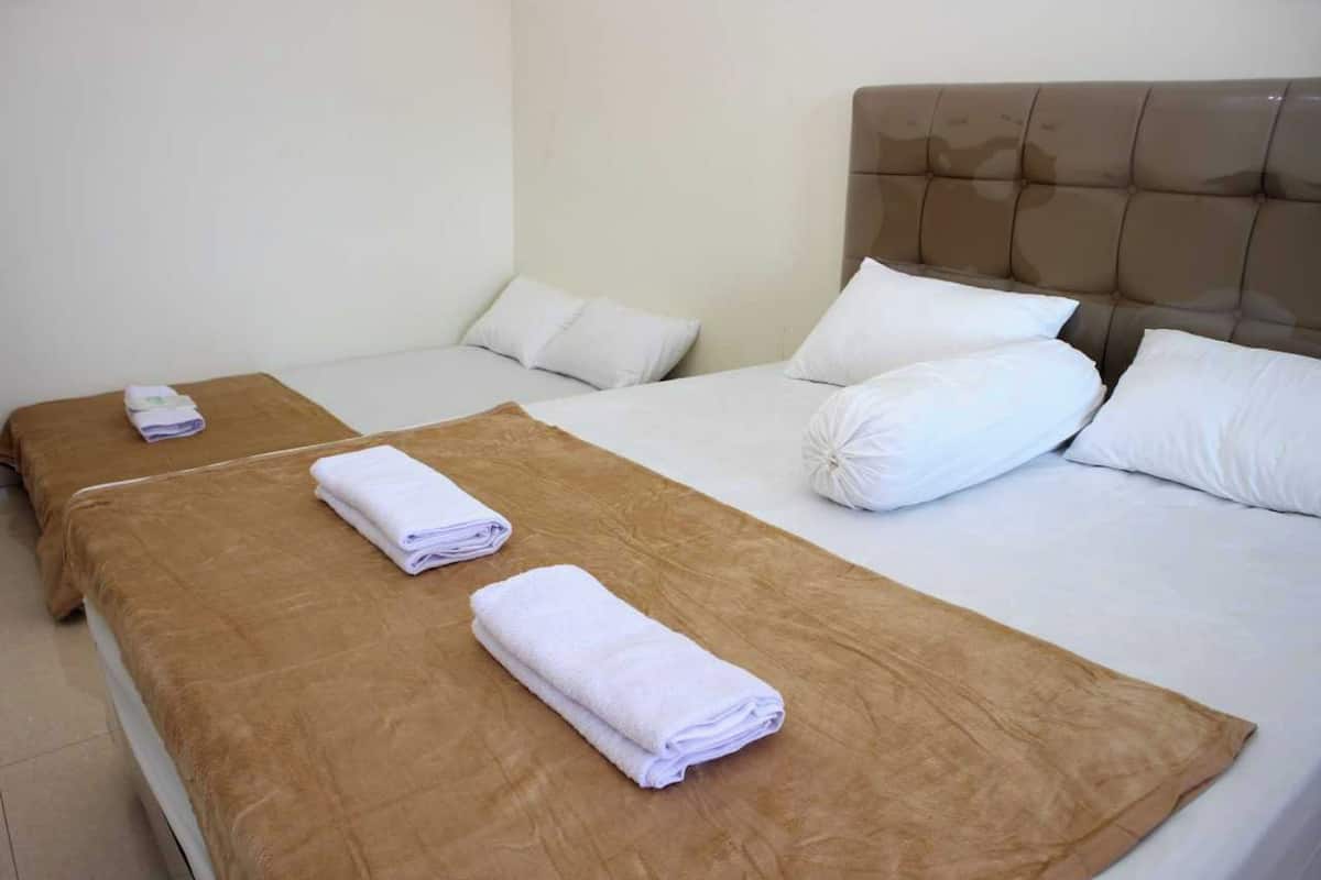 A hotel room with two beds, each with a brown headboard and white bedding.