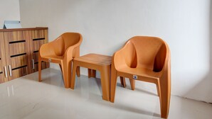 A room with two orange plastic chairs and a small wooden table. - Hotel O Alif House Syariah 2 (Kediri)