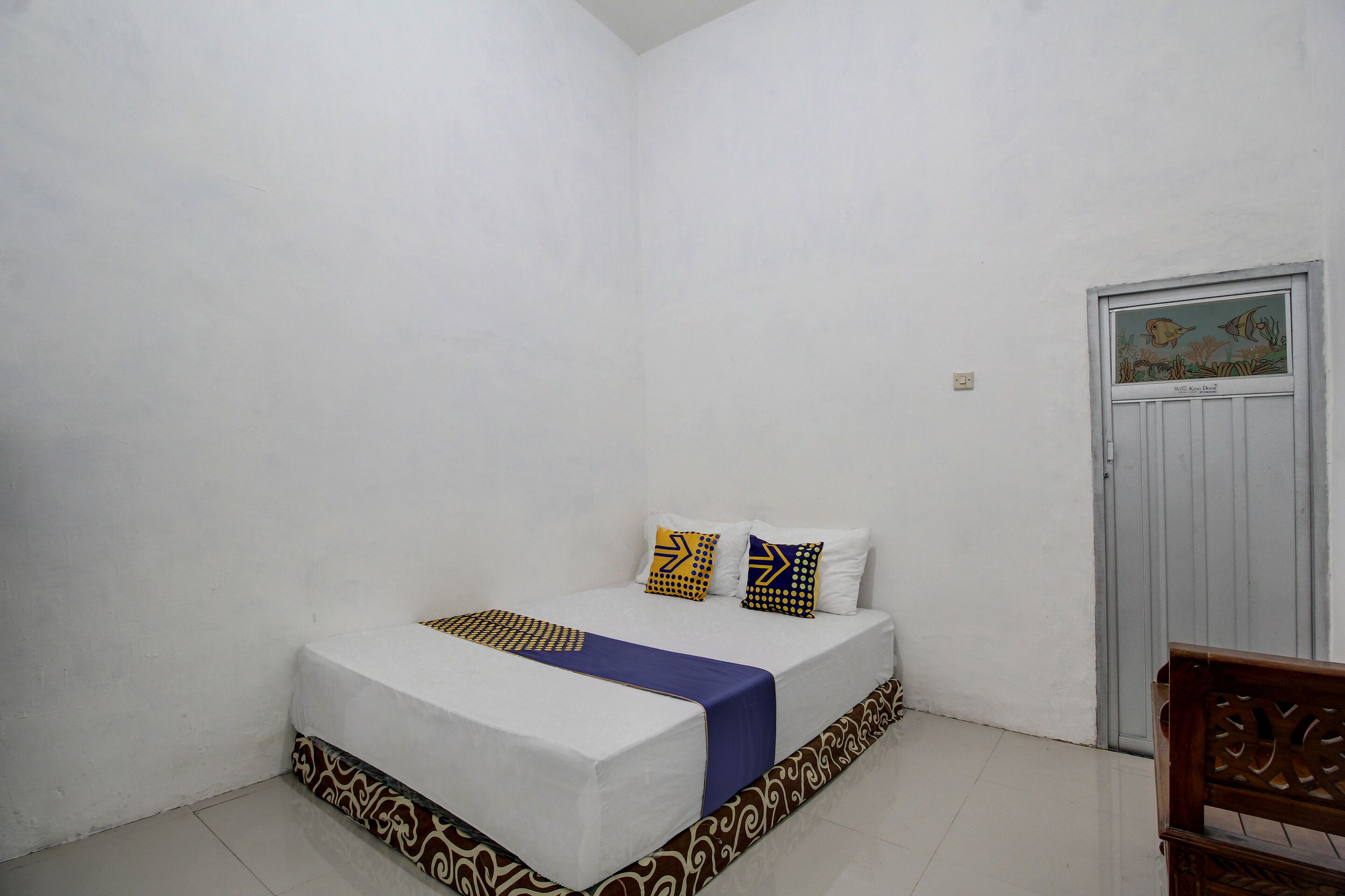 Quarto com uma cama, uma porta com uma imagem e um banco.