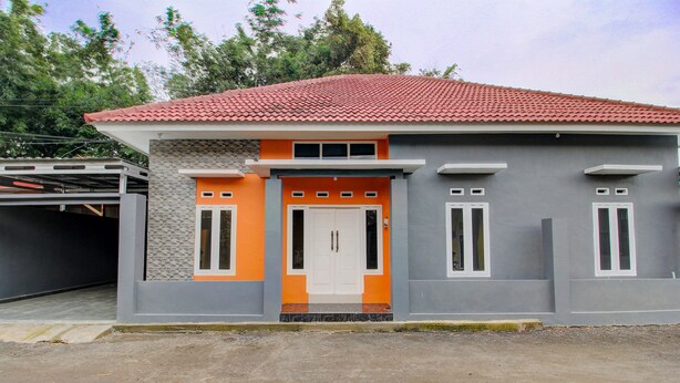 A two-story house with a red-tiled roof, a front door with two windows, and a garage to the left. - Hotel O Alif House Syariah 2 (Kediri)