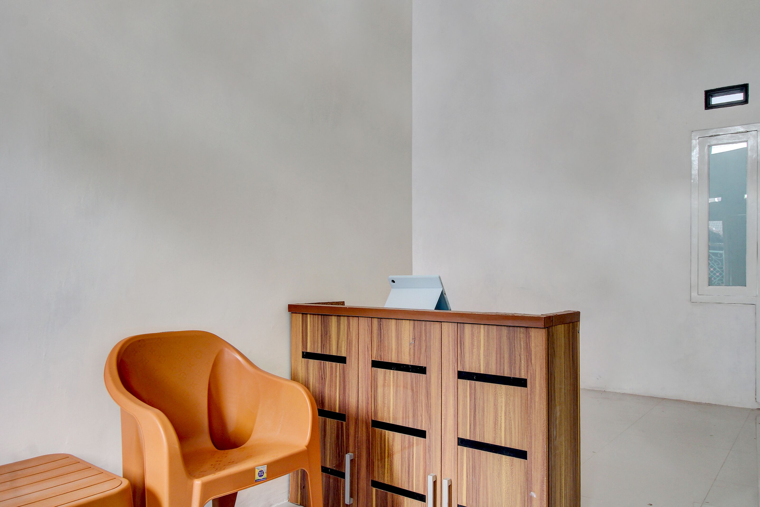 A room with a wooden cabinet, a plastic chair, and a small table.
