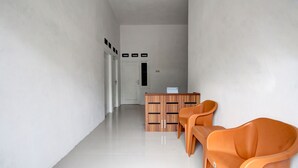 A hallway with a reception desk, a white door, and two orange chairs. - Hotel O Alif House Syariah 2 (Kediri)
