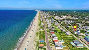An aerial view of a coastal town with a beach, houses, and a road. - Oceanview Hawks Landing in Oak Island: 3BR, 2BA retreat for 6 guests. (Oak Island)