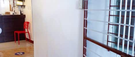 Un pasillo con una mesa de recepción, una silla roja y un suelo de baldosas.