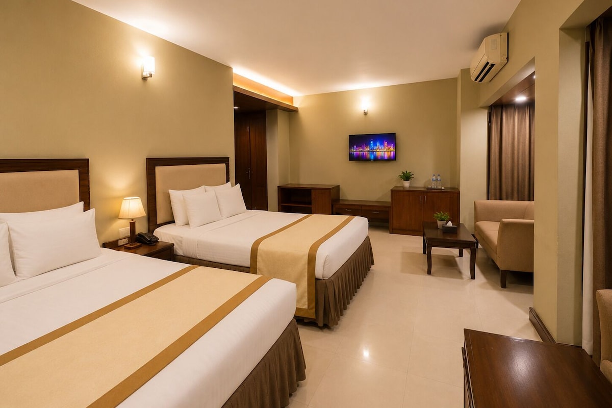 A hotel room with two beds, a television, a desk, a chair, and an air conditioning unit.