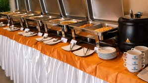 A buffet setup with multiple food dispensers, plates, utensils, and a coffee station. - Hotel Fountain (Dhaka)