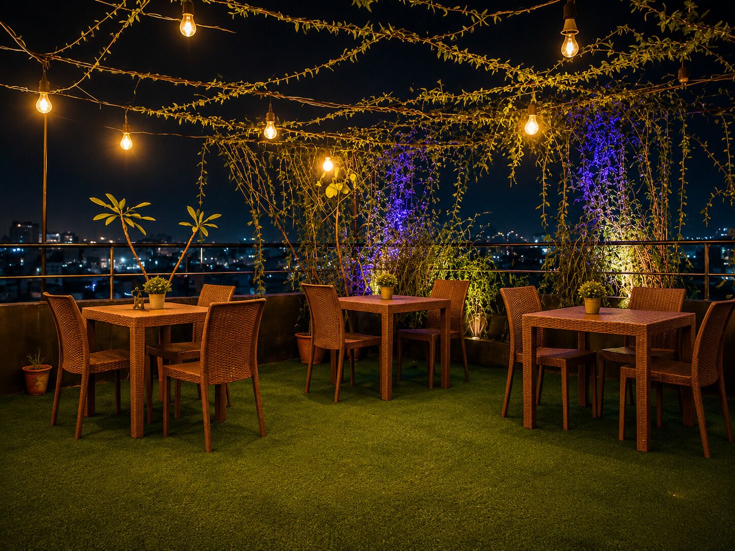 Un área de comedor al aire libre con mobiliario de mimbre y luces colgantes, con vista a un paisaje urbano.