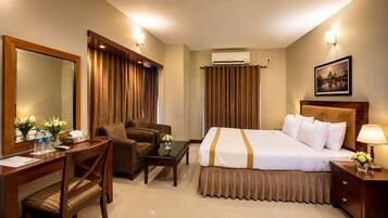 Una habitación de hotel con cama, escritorio, silla, mesa y mesita de noche.