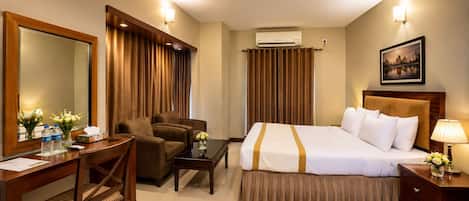 Quarto de hotel com cama, escrivaninha, cadeira, mesa e mesa de cabeceira.
