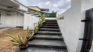 Una escalera que lleva a un edificio de fachada blanca y puerta negra.