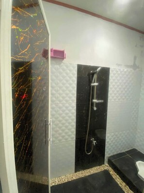 Bathroom features a glass-enclosed shower with a textured black wall and silver showerhead.