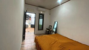 Un dormitorio con una cama, una silla, un espejo y un equipo de aire acondicionado.