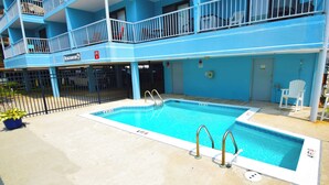 Una piscina con un edificio azul al fondo.