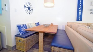 Una habitación acogedora con una mesa de madera, un banco, un sofá y un letrero en la pared.