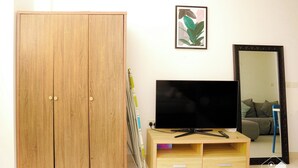 Une pièce comprenant une armoire en bois, un téléviseur posé sur un meuble en bois, un miroir et un tableau encadré accroché au mur.