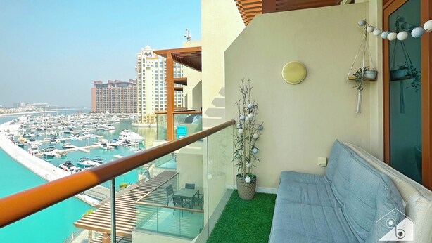 Un balcon donnant sur un port de plaisance, un canapé et un petit jardin intérieur.