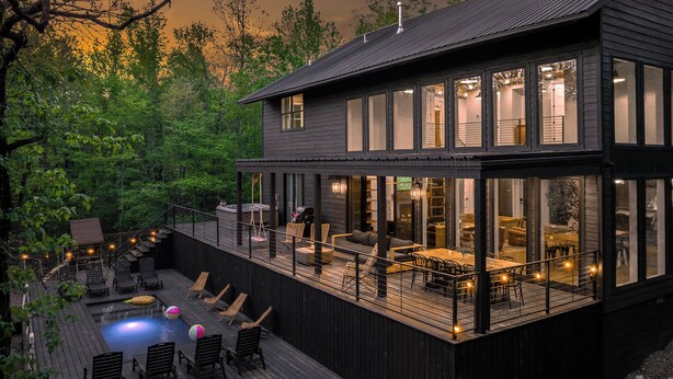 A modern house with a large deck, outdoor seating, and a swimming pool.