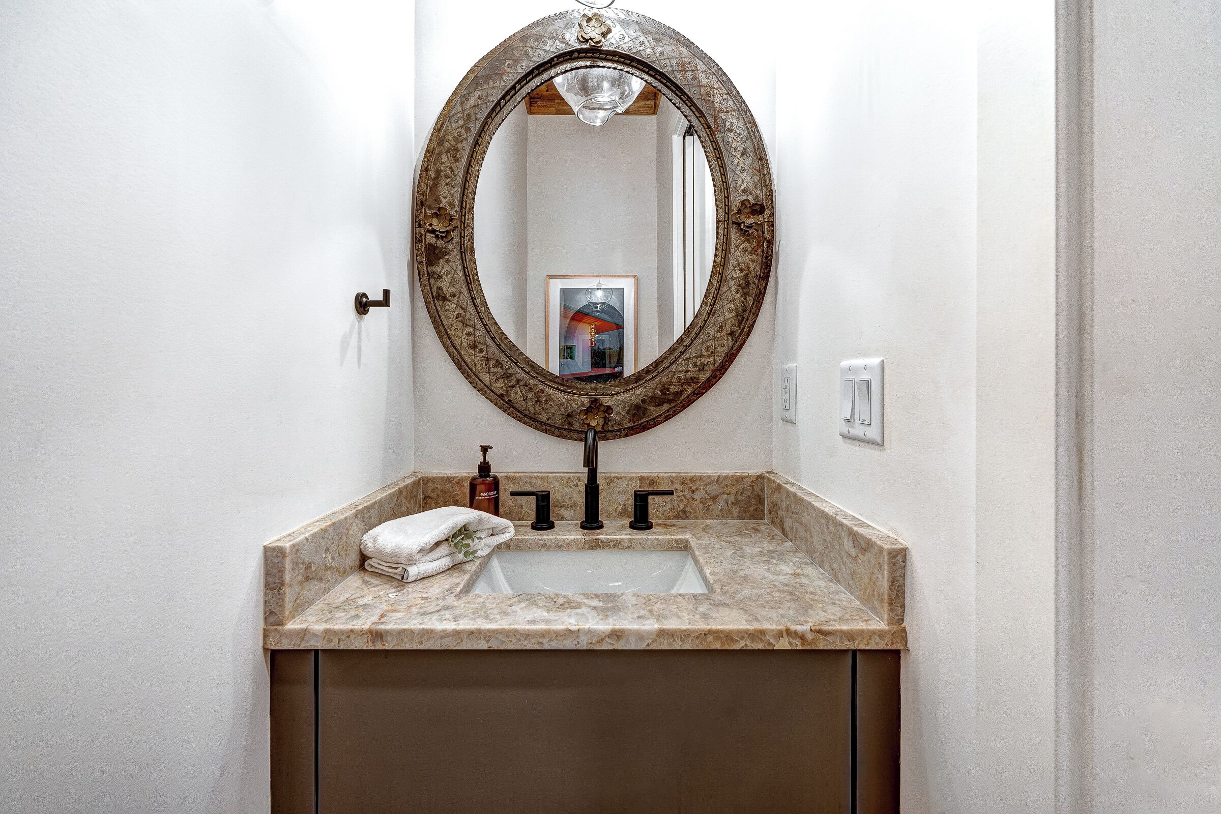 A bathroom with a marble sink, a round mirror, and a towel on the counter.
