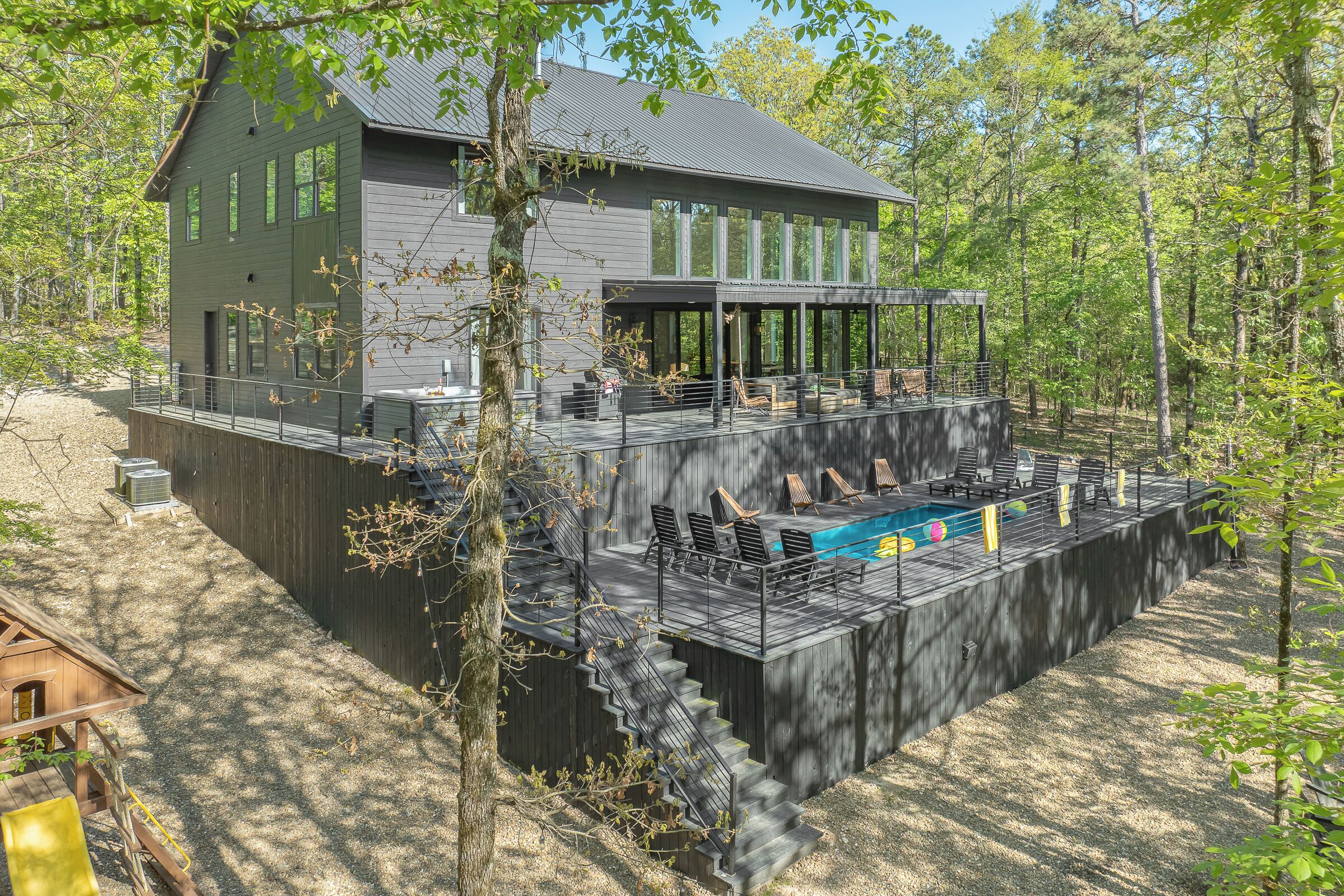 Una casa moderna con una terraza grande, piscina y un espacio exterior cubierto.