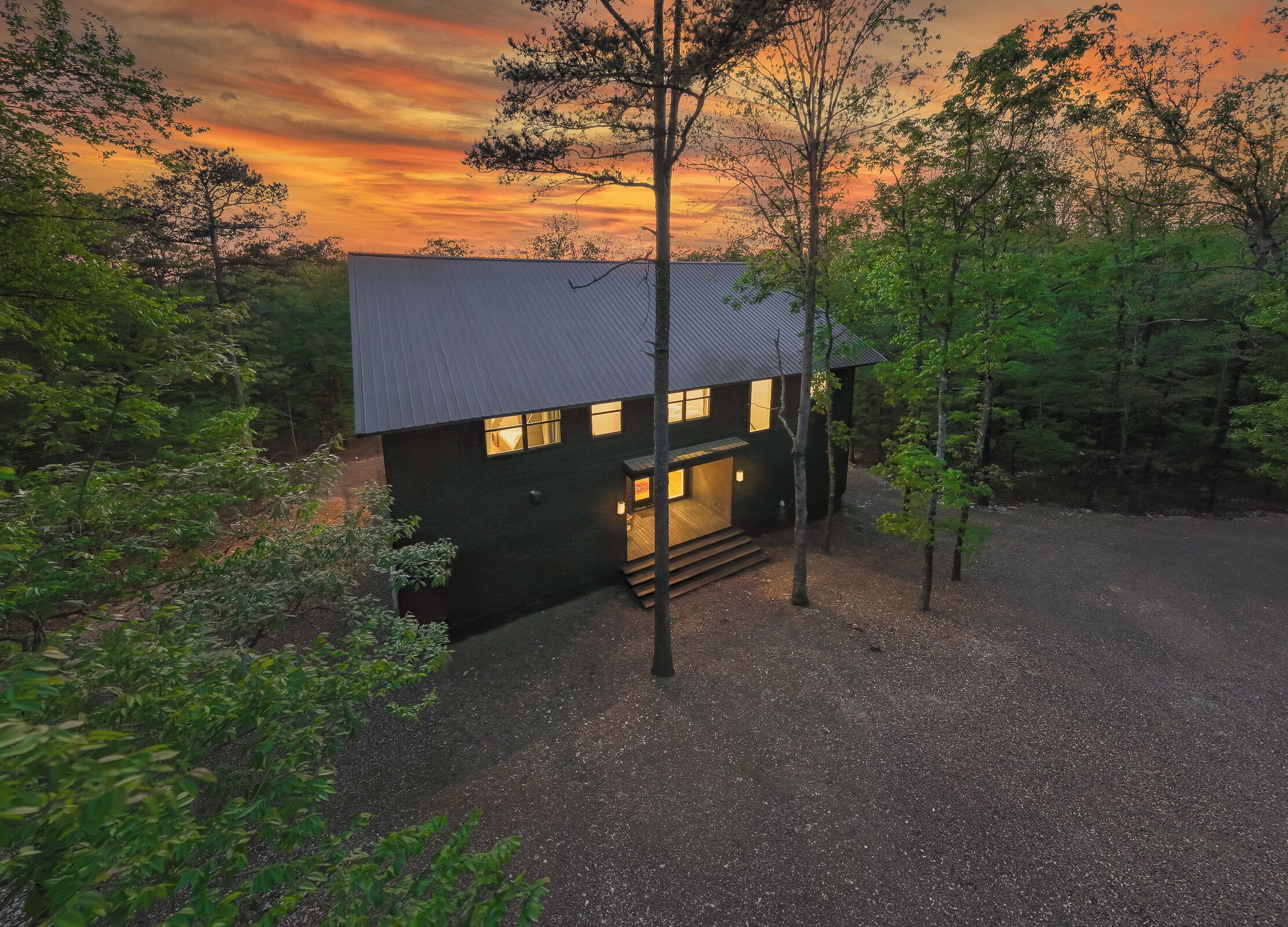 A modern house with a dark exterior, a sloped roof, and a front porch with steps leading to the entrance.