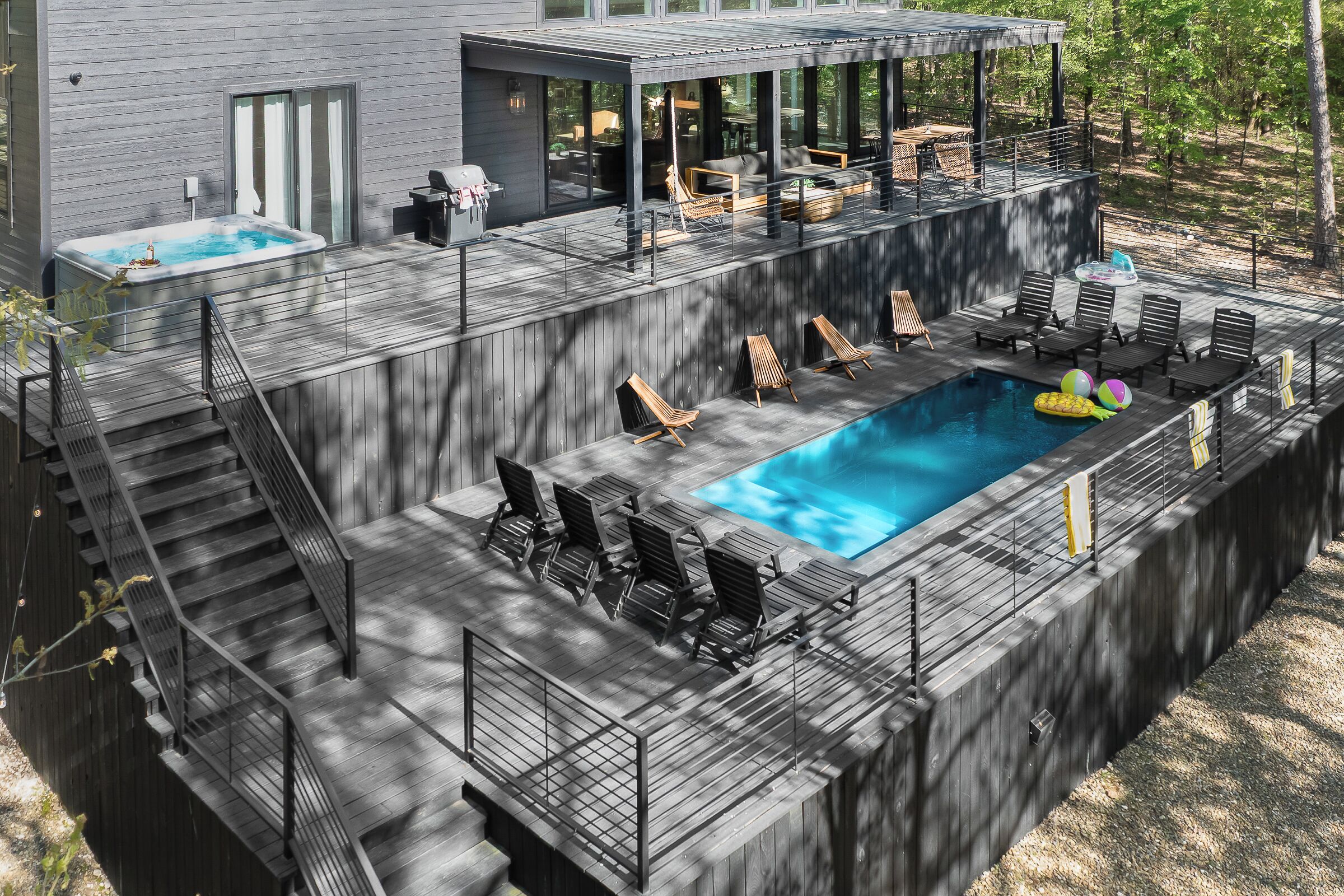Een modern terras met zwembad, buitenmeubels en een jacuzzi.