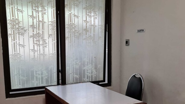 Une pièce comprenant un bureau, une chaise et une fenêtre en verre dépoli ornée d’un motif de bambou.