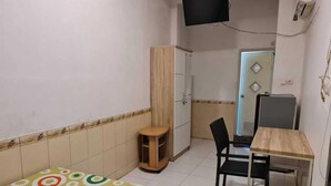 Une petite pièce, simplement aménagée, avec un lit, un bureau, une chaise et une armoire.