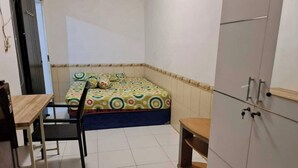 Une petite pièce propre, avec un lit, un bureau et un placard.