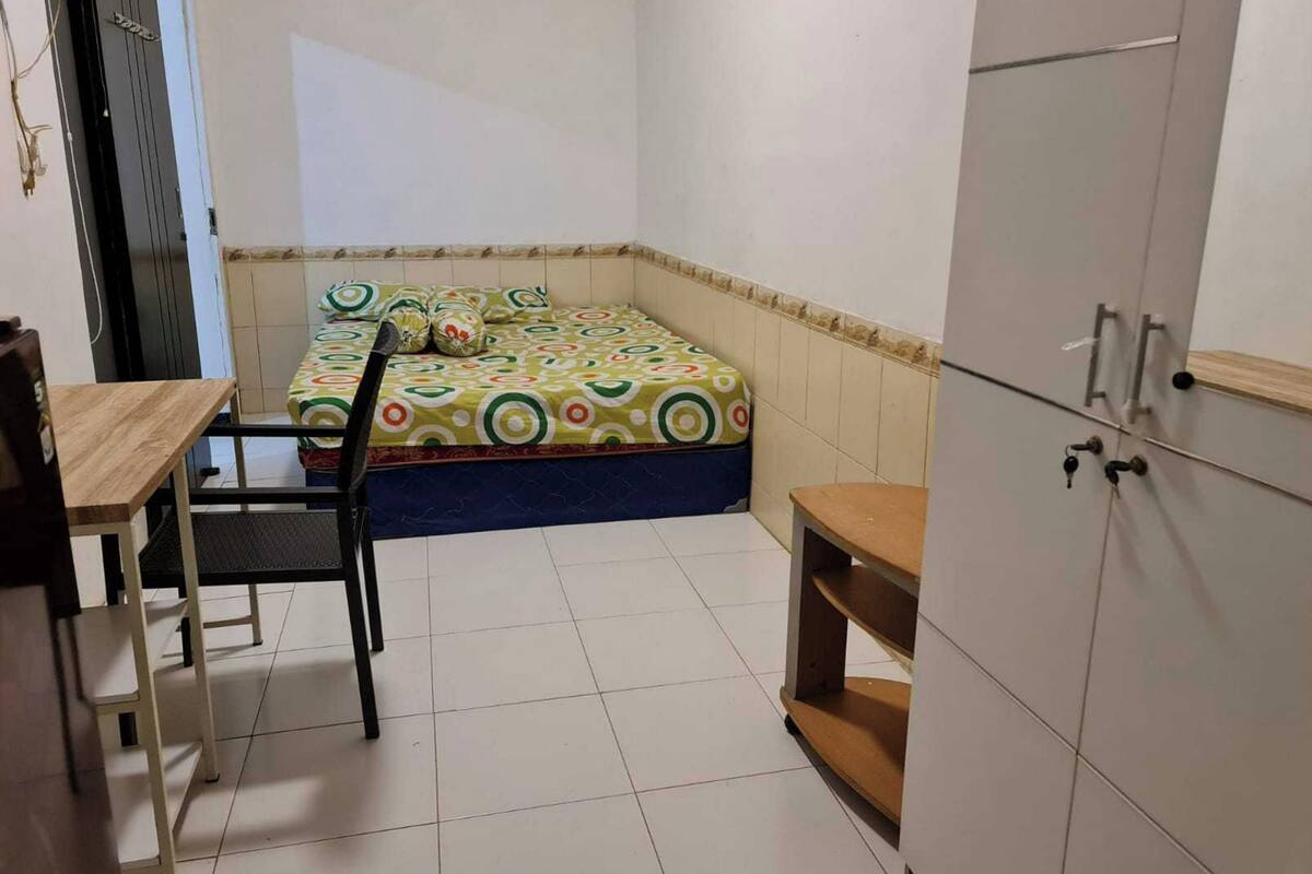 Una habitación pequeña y limpia, con cama, escritorio y armario.