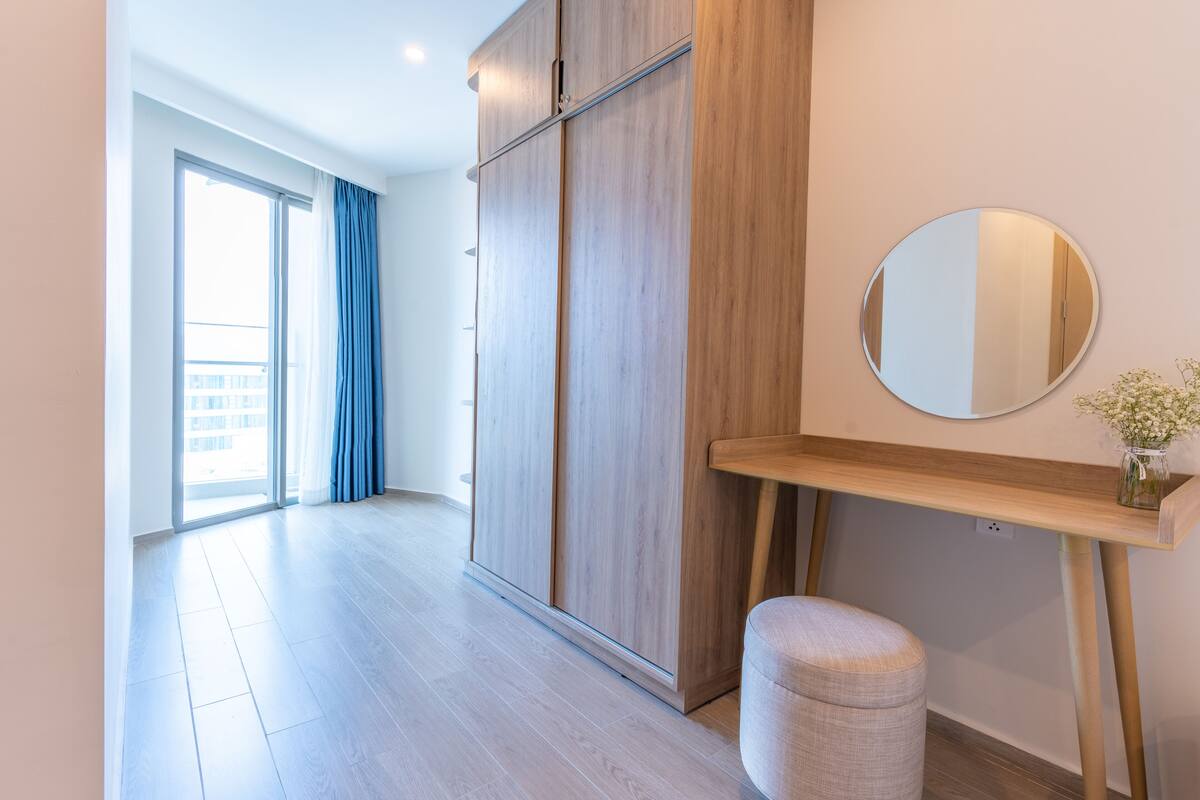 A modern bedroom with a large wardrobe, a round mirror, and a bedside table.