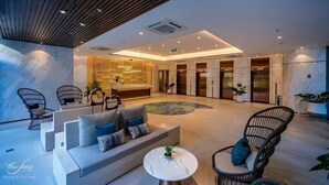Un vestíbulo moderno con un sofá, sillas, una mesa redonda y una zona de recepción.