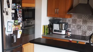 A kitchen with wooden cabinets, a black refrigerator, a stove, a microwave, and a coffee maker. - 1 bedroom apt. of an Artist photographer close to Cannes Croisette (Cannes)